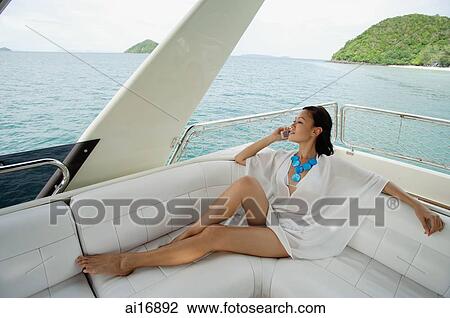 Woman sitting on stern of yacht, using mobile phone View Large Photo Image Stock Image - Woman sitting on stern of yacht, using mobile phone . Fotosearch
