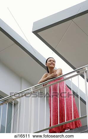 Woman standing on balcony, leaning on railing View Large Photo Image Stock Image - Woman standing on balcony, leaning on railing . Fotosearch
