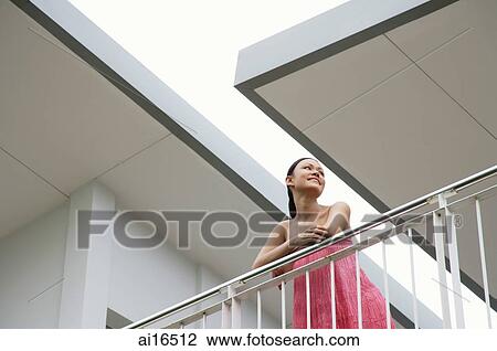 Woman standing on balcony, leaning on railing, looking away View Large Photo Image Stock Image - Woman standing on balcony, leaning on railing, looking away . Fotosearch