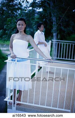 Woman standing on balcony, man leaning on railing in the background View Large Photo Image Stock Image - Woman standing on balcony, man leaning on railing in the background . Fotosearch