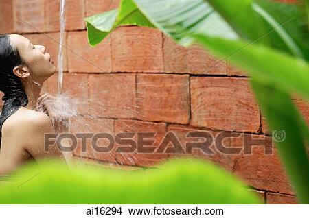 Woman taking a shower, outdoors, framed by leaves View Large Photo Image Picture - Woman taking a shower, outdoors, framed by leaves . Fotosearch