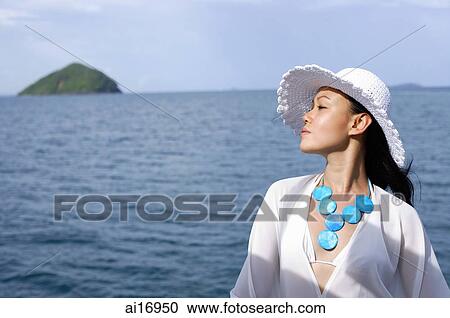 Stock Image - Woman wearing white hat, in profile, ocean behind her . Fotosearch