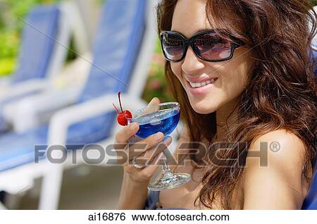 Woman with sunglasses, holding cocktail, smiling View Large Photo Image Stock Photograph - Woman with sunglasses, holding cocktail, smiling . Fotosearch