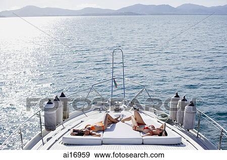 Stock Photo - Women sunbathing on boat deck, high angle view . Fotosearch