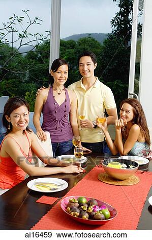 Young adults around dinner table, smiling at camera View Large Photo Image Stock Photo - Young adults around dinner table, smiling at camera. Fotosearch