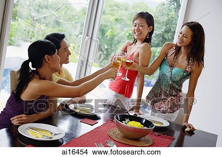 Young adults in dining room toasting with wine glasses View Large Photo Image Picture - Young adults in dining room toasting with wine glasses. Fotosearch