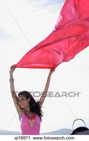 Young woman holding piece of cloth in the air, smiling View Large Photo Image Stock Image - Young woman holding piece of cloth in the air, smiling . Fotosearch