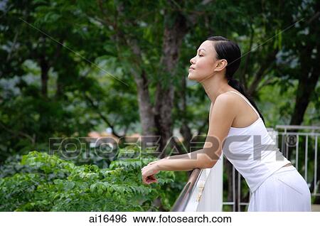 Young woman leaning on railing, looking away View Large Photo Image Stock Photograph - Young woman leaning on railing, looking away . Fotosearch
