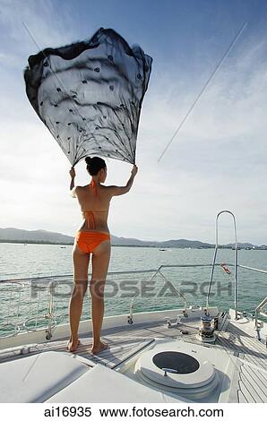 Young woman on windy boat deck, holding out piece of cloth View Large Photo Image Stock Photography - Young woman on windy boat deck, holding out piece of cloth. Fotosearch