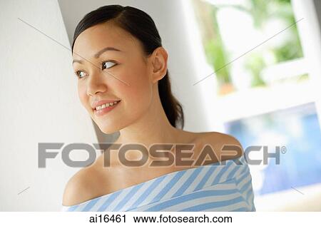 Stock Image - Young woman smiling, looking away . Fotosearch