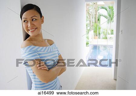 Young woman with arms crossed, smiling, looking away View Large Photo Image Stock Photo - Young woman with arms crossed, smiling, looking away . Fotosearch