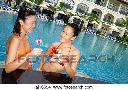 Young women in swimming pool, holding cocktails View Large Photo Image Picture - Young women in swimming pool, holding cocktails . Fotosearch