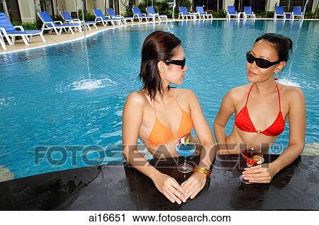 Young women in swimming pool, wearing sunglasses and holding cocktails View Large Photo Image Stock Image - Young women in swimming pool, wearing sunglasses and holding cocktails . Fotosearch
