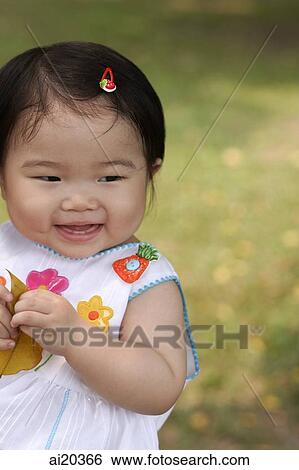 Baby girl holding leaf, smiling View Large Photo Image Stock Photograph - Baby girl holding leaf, smiling. Fotosearch