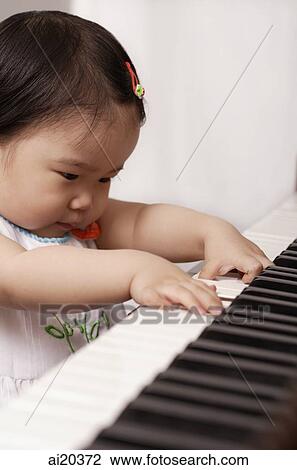 Stock Image - Baby girl playing the piano. Fotosearch
