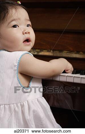Baby girl playing with piano, looking over shoulder View Large Photo Image Stock Image - Baby girl playing with piano, looking over shoulder. Fotosearch