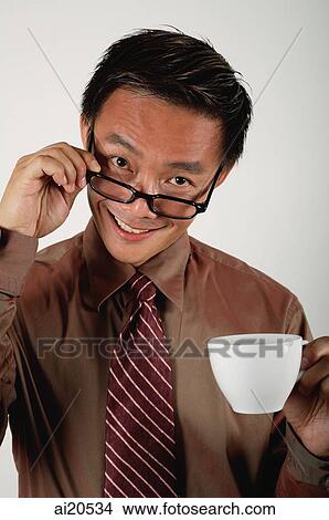 Businessman adjusting glasses and holding cup, smiling at camera View Large Photo Image Picture - Businessman adjusting glasses and holding cup, smiling at camera. Fotosearch