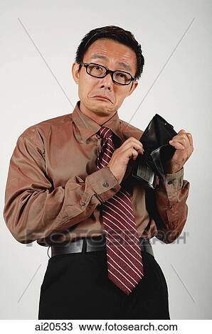 Stock Image - Businessman holding empty wallet, frowning. Fotosearch