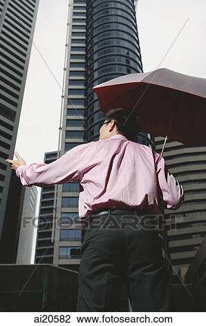 Businessman holding umbrella, rear view View Large Photo Image Stock Image - Businessman holding umbrella, rear view. Fotosearch