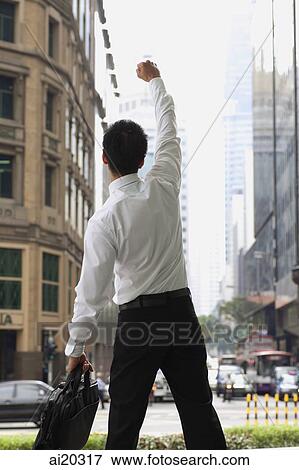 Stock Photo - Businessman in the city, raising one arm and making a fist. Fotosearch