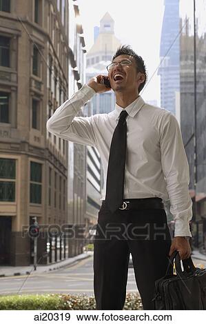 Businessman in the city, using mobile phone View Large Photo Image Stock Photo - Businessman in the city, using mobile phone. Fotosearch