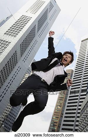 Businessman jumping with arms raised, buildings in the background View Large Photo Image Stock Photo - Businessman jumping with arms raised, buildings in the background. Fotosearch