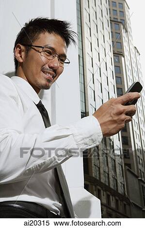 Businessman looking at mobile phone View Large Photo Image Stock Photography - Businessman looking at mobile phone. Fotosearch