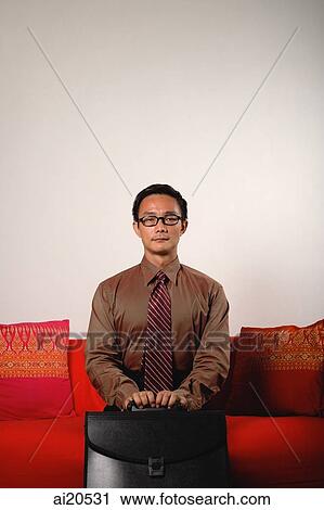Businessman sitting on sofa, holding briefcase View Large Photo Image Stock Image - Businessman sitting on sofa, holding briefcase. Fotosearch
