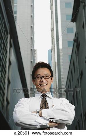 Businessman standing with arms crossed, smiling at camera View Large Photo Image Stock Image - Businessman standing with arms crossed, smiling at camera. Fotosearch