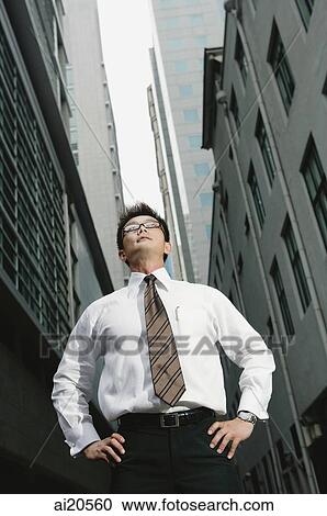 Businessman standing with hands on hips, looking away View Large Photo Image Stock Image - Businessman standing with hands on hips, looking away. Fotosearch