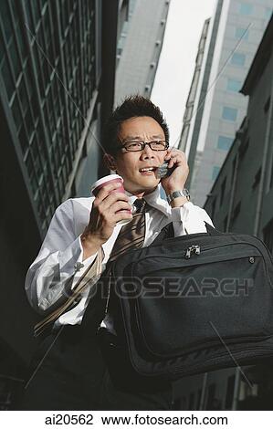Businessman using mobile phone, buildings around him View Large Photo Image Stock Image - Businessman using mobile phone, buildings around him. Fotosearch