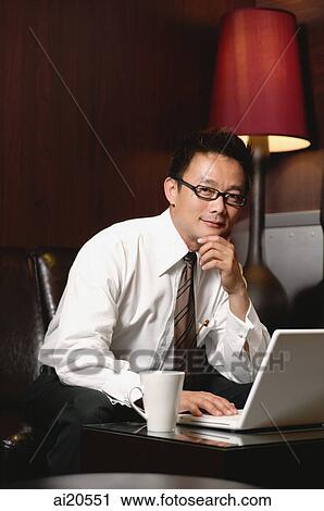 Businessman with laptop, hand on chin, looking at camera View Large Photo Image Stock Image - Businessman with laptop, hand on chin, looking at camera. Fotosearch