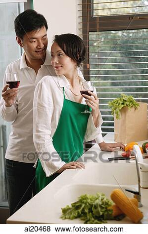 Couple in kitchen holding wine glasses, woman turning to look at man View Large Photo Image Stock Photo - Couple in kitchen holding wine glasses, woman turning to look at man. Fotosearch