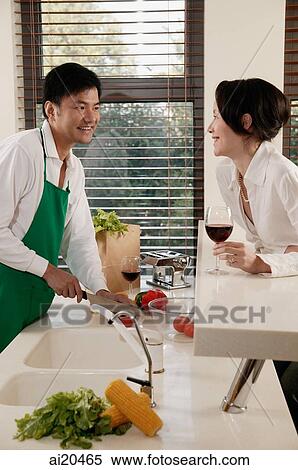 Couple in kitchen, man chopping vegetables, woman leaning on counter with wine glass View Large Photo Image Stock Photography - Couple in kitchen, man chopping vegetables, woman leaning on counter with wine glass. Fotosearch