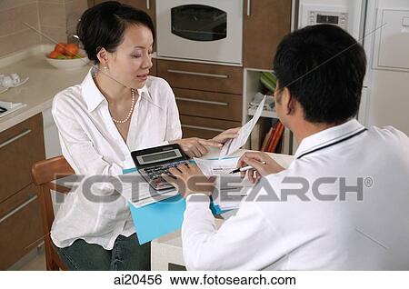 Couple in kitchen, paying bills View Large Photo Image Stock Photograph - Couple in kitchen, paying bills. Fotosearch