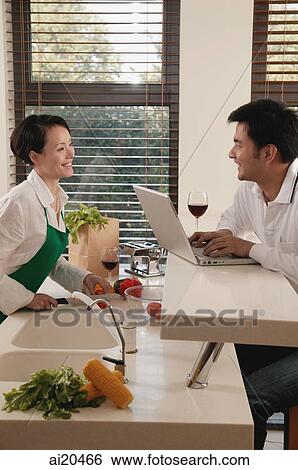 Couple in kitchen, woman chopping vegetables, man using laptop View Large Photo Image Stock Photograph - Couple in kitchen, woman chopping vegetables, man using laptop. Fotosearch