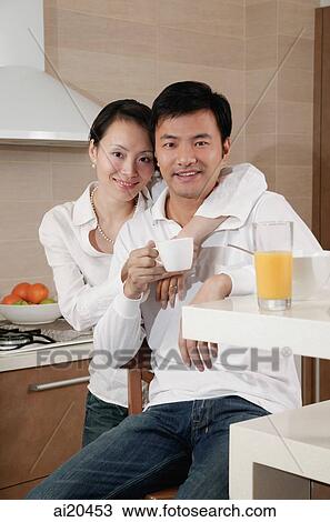 Couple in kitchen, woman with arm around man's shoulder, smiling at camera View Large Photo Image Stock Image - Couple in kitchen, woman with arm around man's shoulder, smiling at camera. Fotosearch