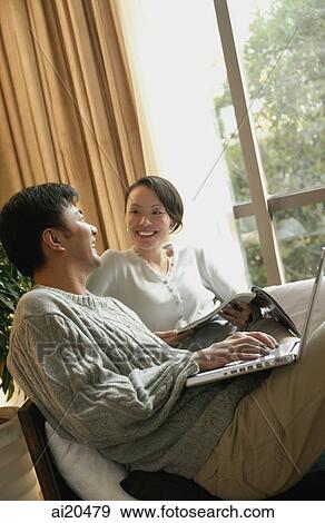 Couple in living room, sitting side by side View Large Photo Image Stock Photo - Couple in living room, sitting side by side. Fotosearch