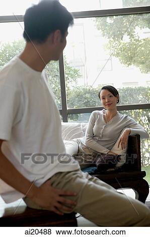 Couple in living room, woman reclining on sofa, man in foreground turning to look at her View Large Photo Image Stock Photo - Couple in living room, woman reclining on sofa, man in foreground turning to look at her. Fotosearch