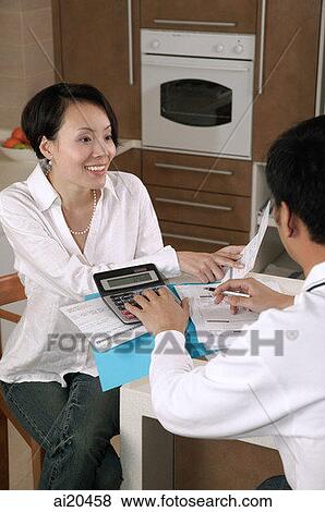 Couple sitting at kitchen table, looking at bills View Large Photo Image Stock Photo - Couple sitting at kitchen table, looking at bills. Fotosearch