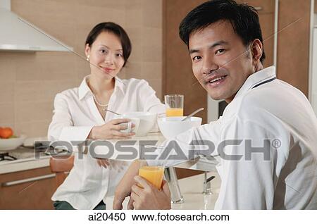 Couple sitting in kitchen with breakfast, looking at camera View Large Photo Image Stock Image - Couple sitting in kitchen with breakfast, looking at camera. Fotosearch