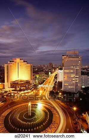Stock Image - Early evening view of the Hotel Indonesia roundabout, Welcome monument and buildings along Jalan Thamrin, Jakarta. Fotosearch