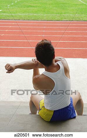 Male athlete sitting down, stretching, running track in the background View Large Photo Image Stock Image - Male athlete sitting down, stretching, running track in the background. Fotosearch