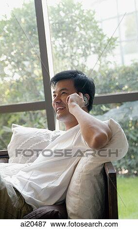 Man at home, sitting on sofa, using mobile phone View Large Photo Image Stock Photo - Man at home, sitting on sofa, using mobile phone. Fotosearch