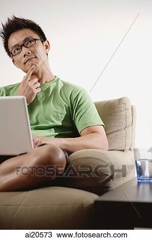 Man at home, using laptop, hand on chin View Large Photo Image Stock Image - Man at home, using laptop, hand on chin. Fotosearch