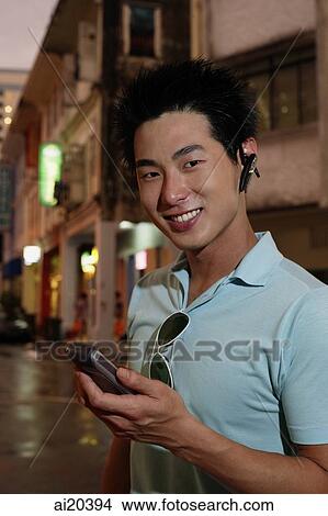 Man holding PDA and wearing Bluetooth device View Large Photo Image Picture - Man holding PDA and wearing Bluetooth device. Fotosearch