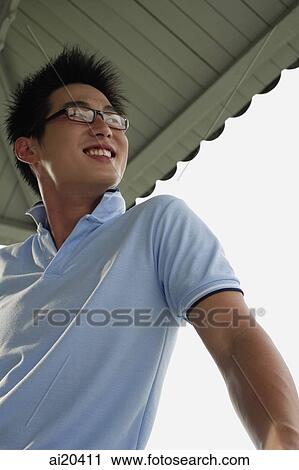 Stock Image - Man in blue polo shirt, looking away. Fotosearch