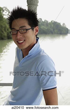 Stock Image - Man in blue polo shirt, smiling, river behind him. Fotosearch