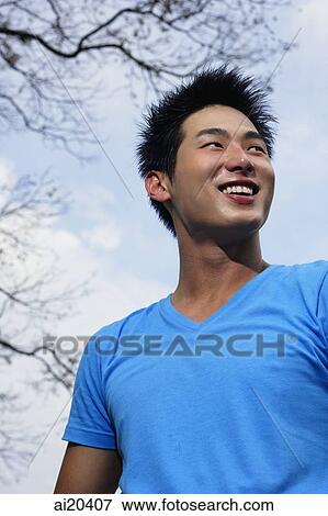 Man in blue T-shirt, smiling, looking away View Large Photo Image Stock Photo - Man in blue T-shirt, smiling, looking away. Fotosearch