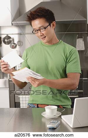 Man in kitchen, looking at bills, laptop on the kitchen counter View Large Photo Image Stock Photograph - Man in kitchen, looking at bills, laptop on the kitchen counter. Fotosearch